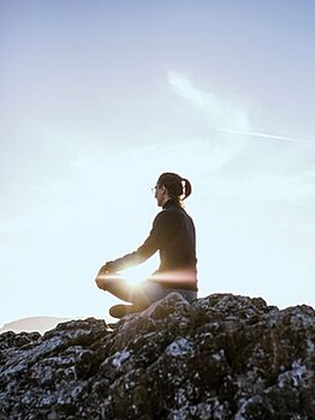 person sitting on rock thinking about tjoughts